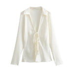 A white, long-sleeve, tie-front shirt with a collared neckline.