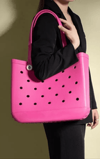 Person holding a pink tote bag with black polka dots against a neutral background