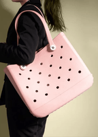 Pink polka dot handbag held by a person against a neutral background