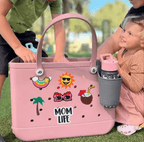 Pink tote bag with 'Mom Life' and stickers, held by a child outdoors.