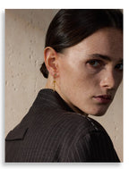 Woman wearing a gold earring with a neutral background