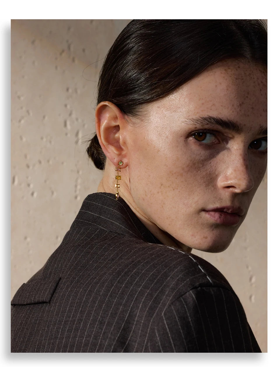 Woman wearing a gold earring with a neutral background