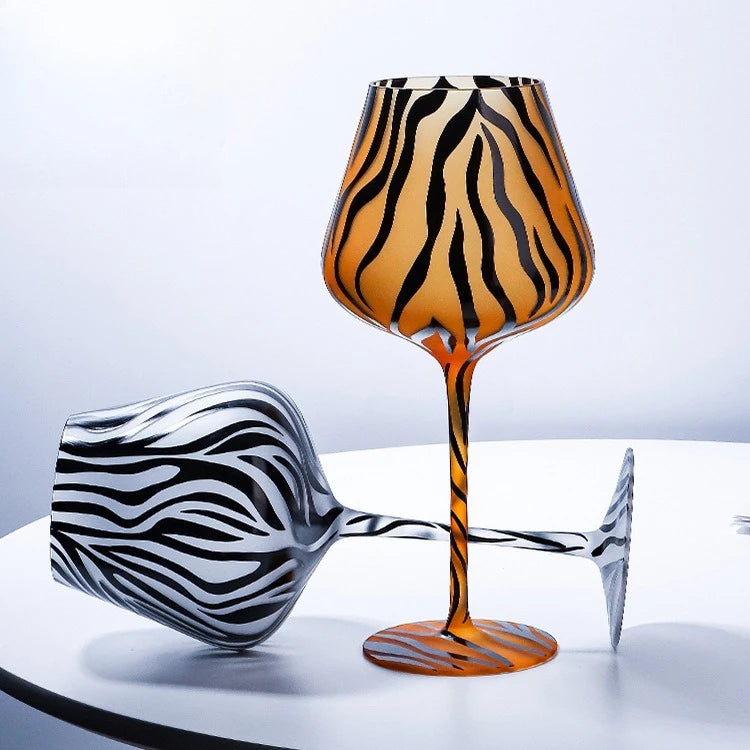 Glowing zebra-striped wine glass on a reflective surface with a gradient background