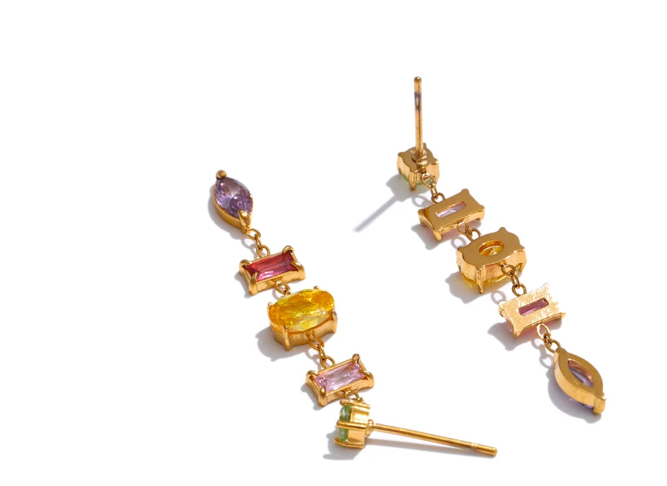 Gold earrings with colorful gemstones on a white background