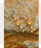Multicolored gemstone earrings on a textured stone surface with 'FASHION ACCESSORIES' text above.