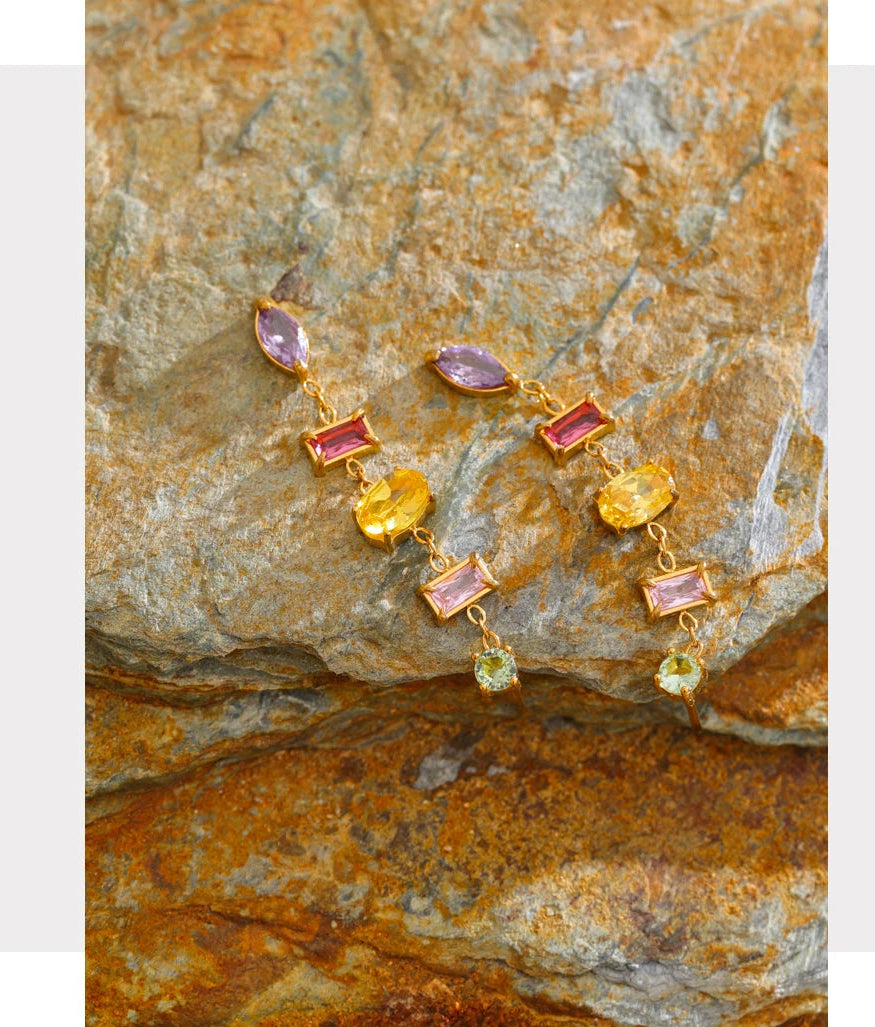 Multicolored gemstone earrings on a textured stone surface with 'FASHION ACCESSORIES' text above.