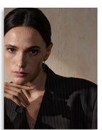 Woman wearing a black pinstripe shirt against a beige wall