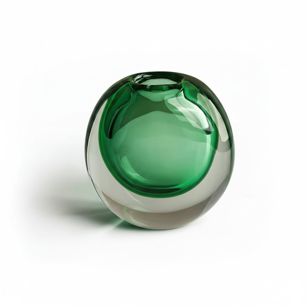 Green glass sphere vase on a white surface with a beige background