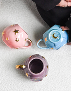 Three ceramic mugs with star and moon designs on a textured surface.