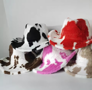 Five cow-patterned cowboy hats in different colours on a white background