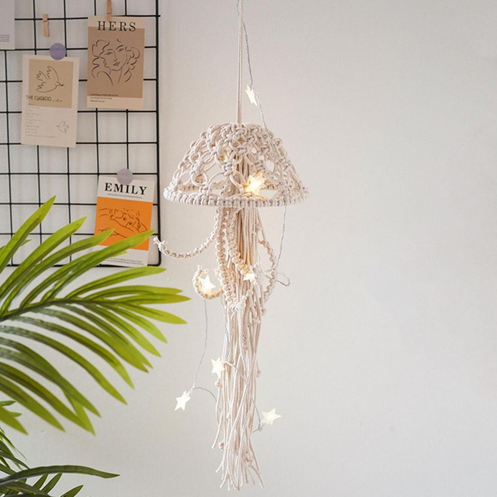 Macrame string light with decorative lampshade hanging against a white wall with a plant and name cards.