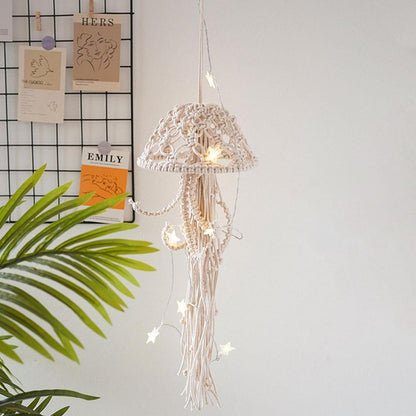 Macrame string light with decorative lampshade hanging against a white wall with a plant and name cards.