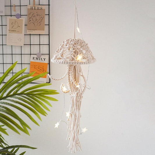 Macrame string light with decorative lampshade hanging against a white wall with a plant and name cards.