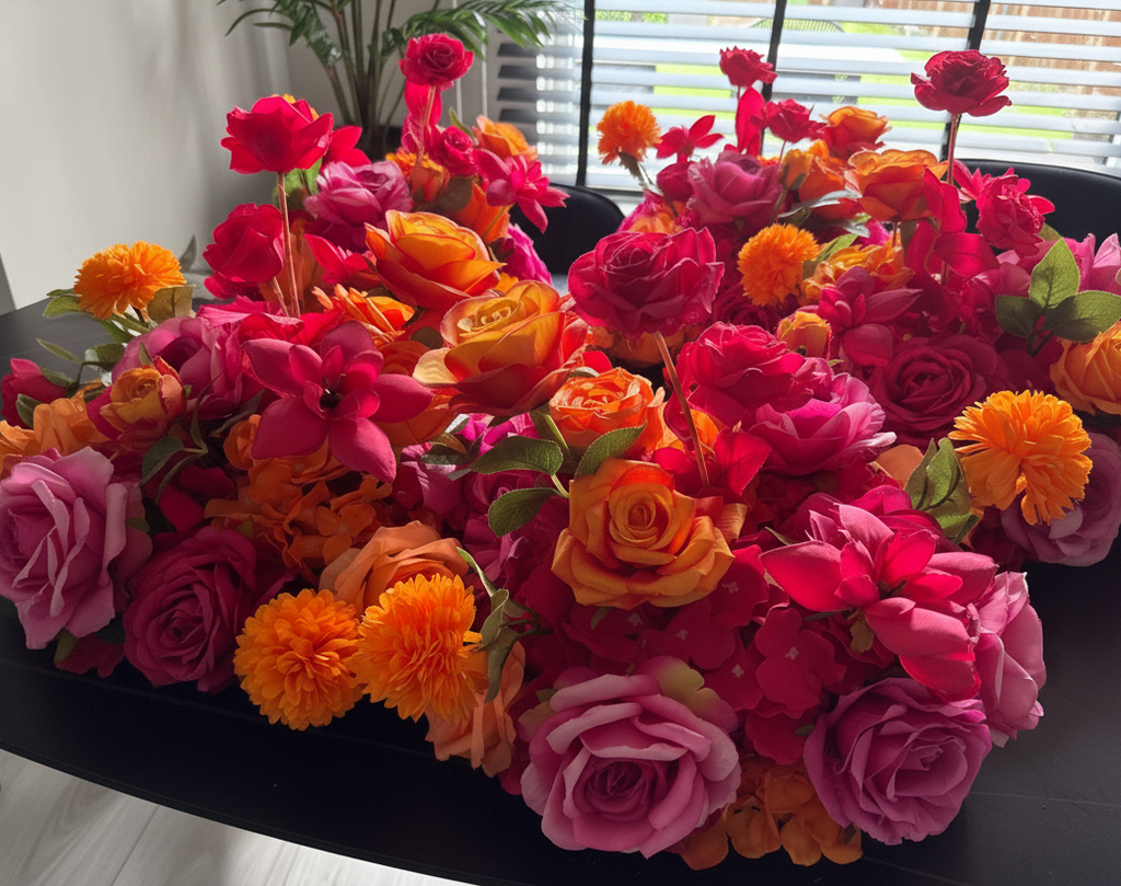 Colorful artificial flowers arranged in a decorative manner on a dark surface.