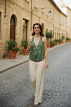 Woman in a green top and beige pants walking down a cobblestone street.